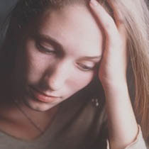 A girl with depression holding her head and looking sad.